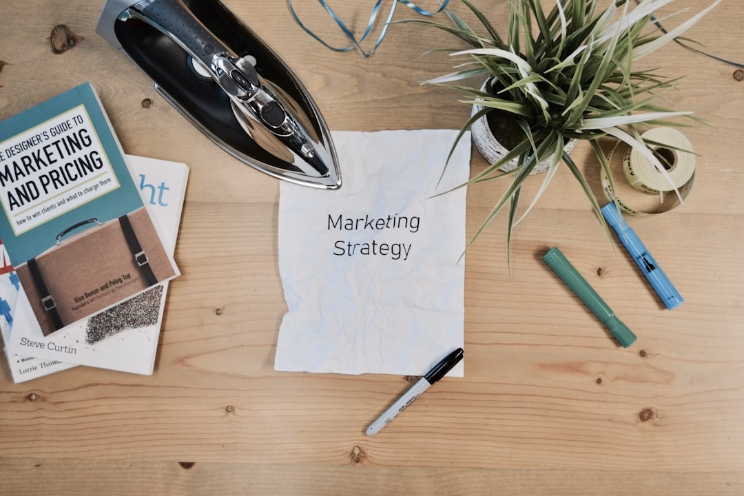 Desk with a handwritten Marketing Strategy note, a marketing and pricing book and a plant