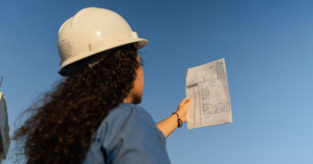 Contractor in a hard hat holding job site plans