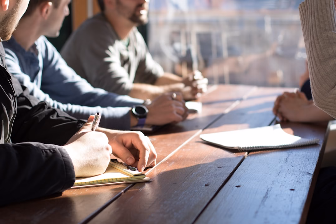 Team members taking notes around a wooden table during a planning meeting