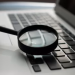Magnifying glass over a laptop, representing testing and validating schema markup