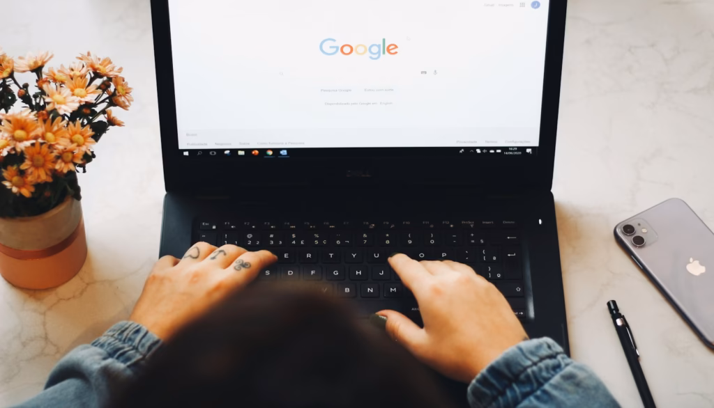 Hands typing on a laptop with the Google homepage open to run a site: search