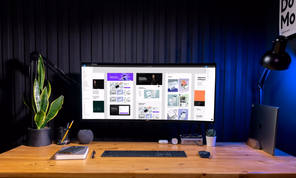 Desktop monitor on a wooden desk showing interface layouts in a design workspace