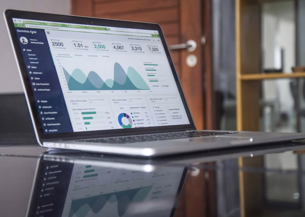 Laptop on a glass table showing ad campaign analytics charts for paid advertising platforms